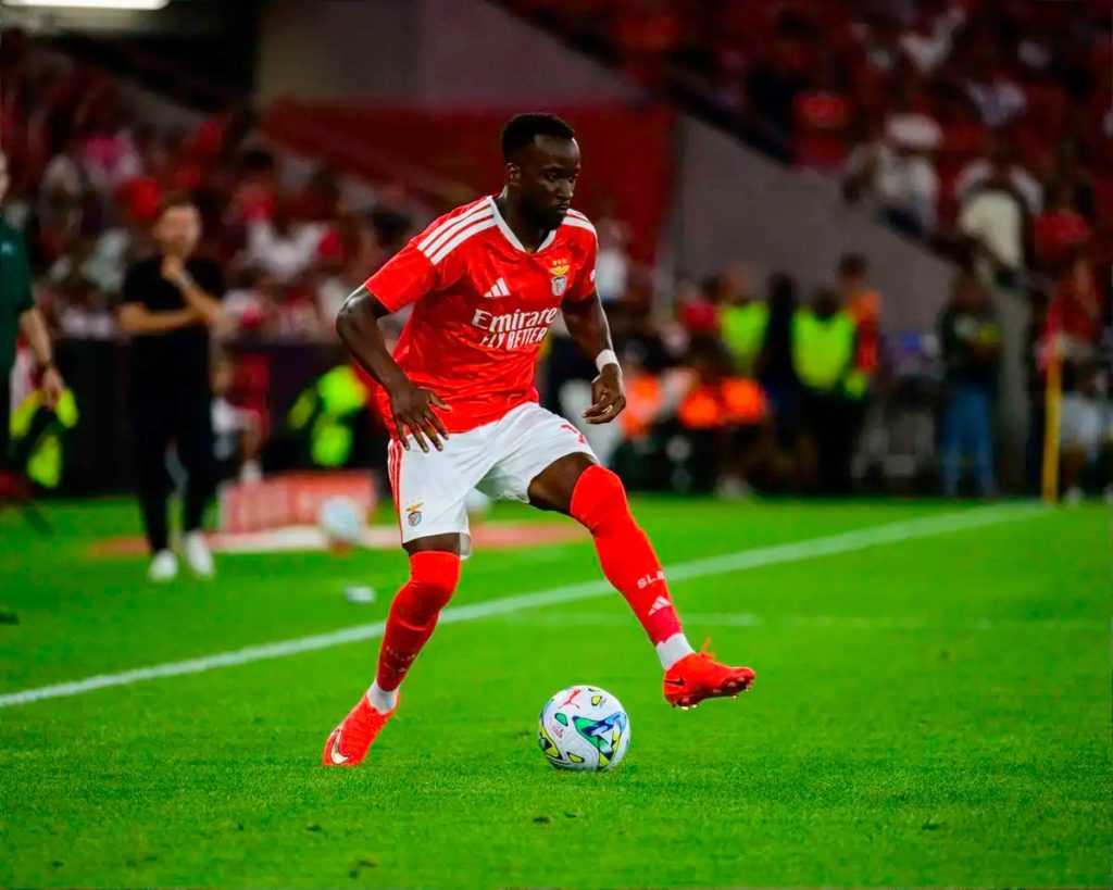 Jogador do Benfica de equipamento vermelho controla a bola em campo, durante jogo da Liga Europa.