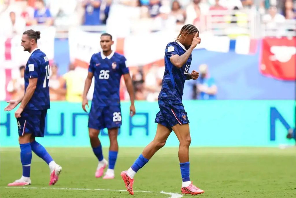 Jogadores de azul com o número 12 e 26 num relvado; um deles cobre o rosto com a mão, em jogo de seleção francesa.