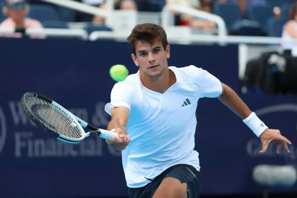 Tennis player in white Adidas shirt and wristband hitting a forehand with a blue-and-black racket at a Western & Southern Financial event.