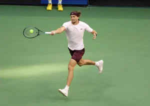 Alexander Zverev in white and maroon hits a forehand on a green hard court at the China Open tennis tournament.