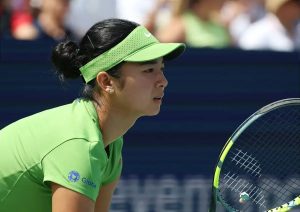 Tennis player in green visor and green Globe-branded shirt leaning forward with a racket on a tournament court. Article subject: Alex Eala.