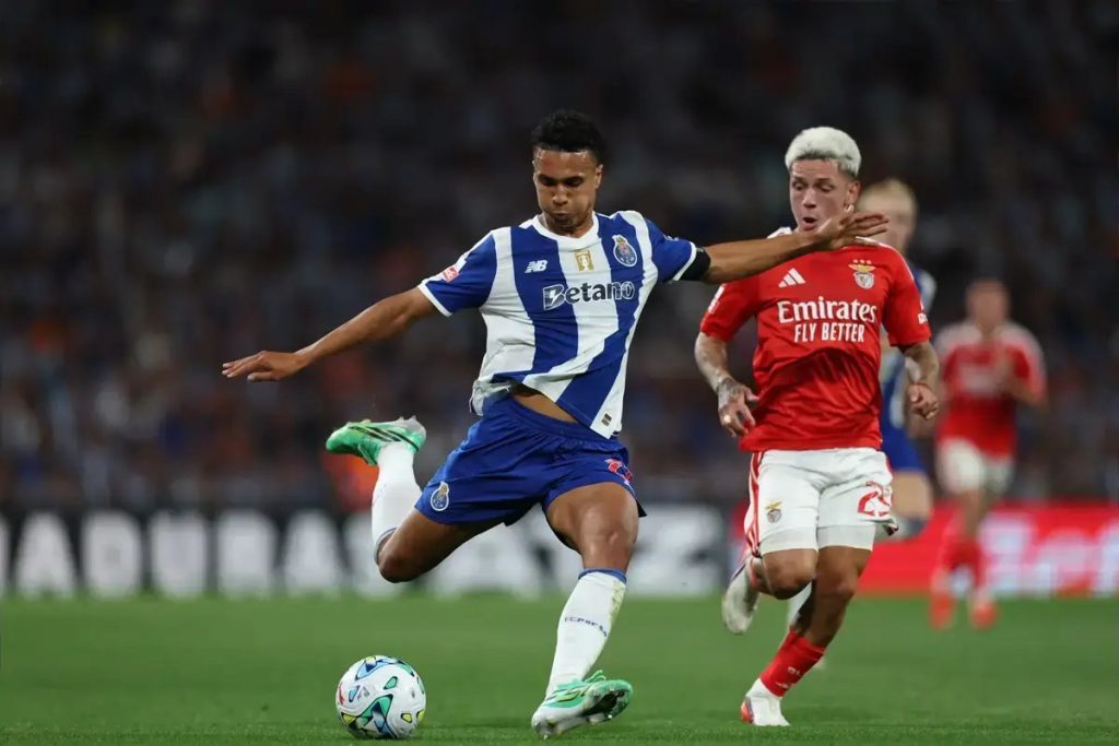 Porto player in blue and white kit shooting at goal while a Benfica player in red pressures him during a Portuguese league match