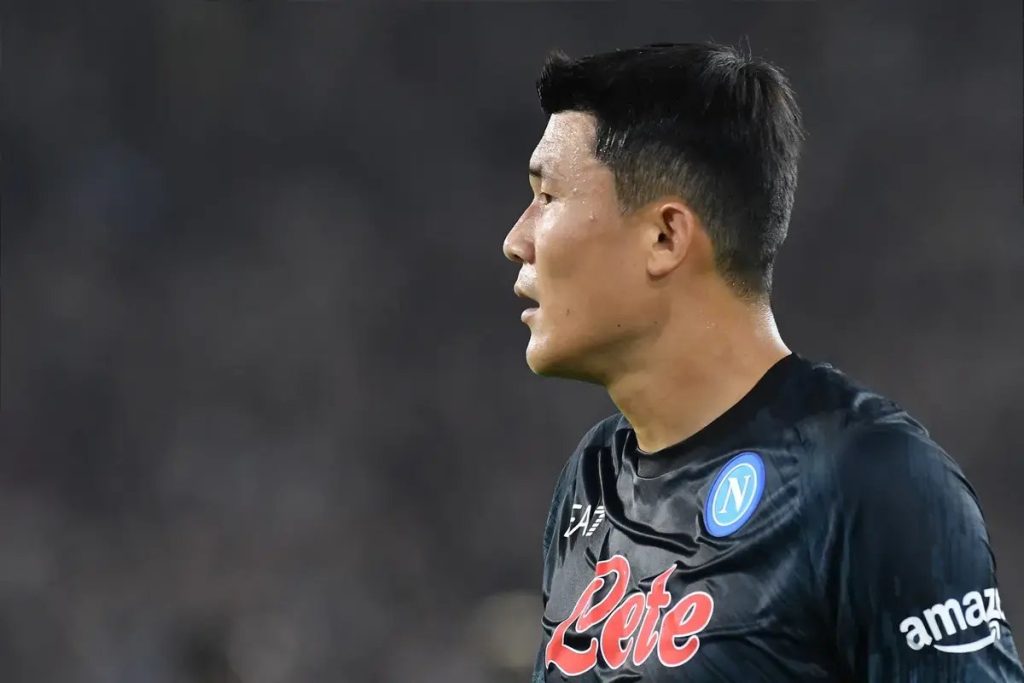 Kim Min-jae in a dark Napoli kit with the club crest and Lete sponsor, looking to the side at a match.