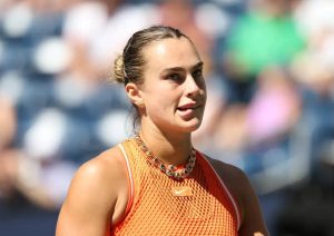 Aryna Sabalenka in an orange Nike top and jeweled necklace during a match at the China Open tennis tournament in Beijing