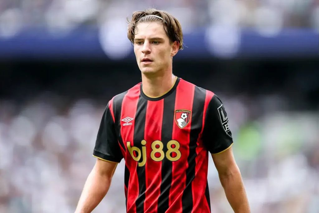 Alex Scott in a red and black striped Bournemouth kit with bj88 sponsor, looking ahead at a blurred stadium crowd