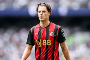 Alex Scott in a red and black striped Bournemouth kit with bj88 sponsor, looking ahead at a blurred stadium crowd
