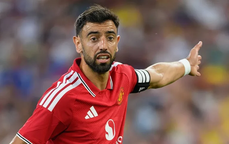 Jogador de camisola vermelha do Manchester United, com braço estendido, num estádio, durante um jogo.