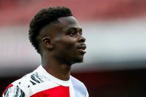 Bukayo Saka in Arsenal's red and white kit, looking to the side during a match at the stadium