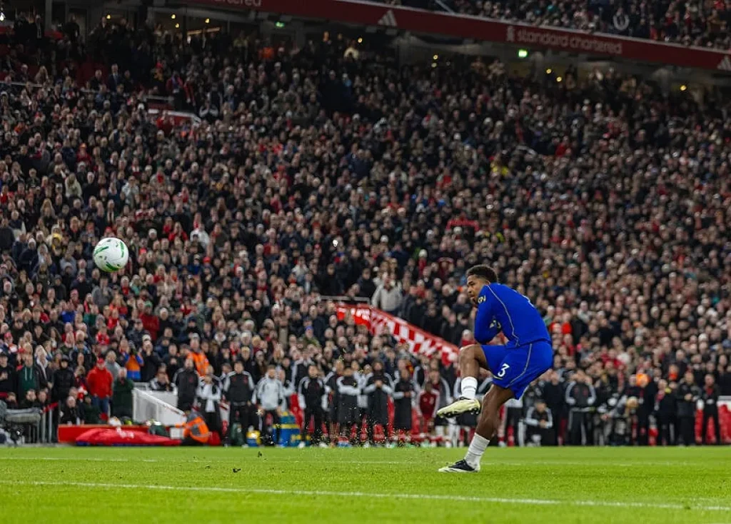 Jogador do Chelsea, de azul e número 3, a bater um livre num estádio cheio de adeptos.