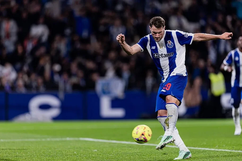 Jogador do FC Porto, de camisola azul e branca n.º 19, remata à baliza num estádio com adeptos ao fundo