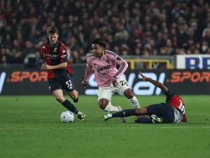 Jogador da Juventus de camisola rosa (n.º 22) tenta fugir a um adversário do Génova de camisola rubro-azul (n.º 32) num lance em campo.