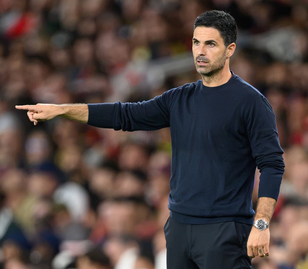 Mikel Arteta pointing and gesturing on the touchline during an Arsenal match, in a crowded stadium
