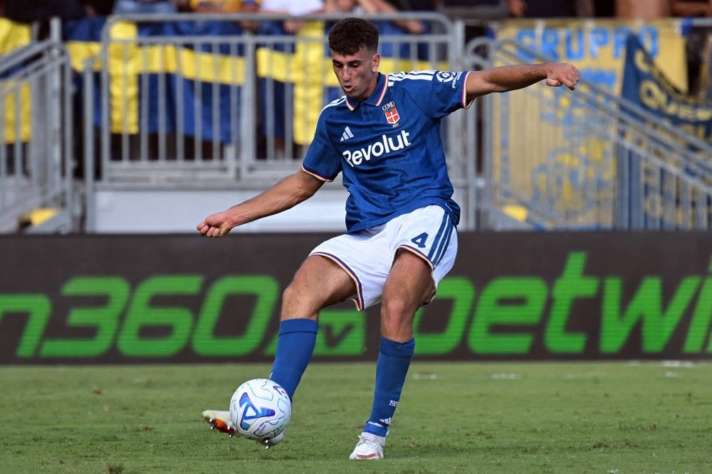 Jacobo Ramon in blue Celta Vigo-style kit with number 4 strikes the ball during a match, grass pitch and stadium behind him
