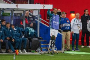 Man in green training top and bib on Portugal's bench, arm raised, at a UEFA Nations League match. Identifying him by face isn't possible here.