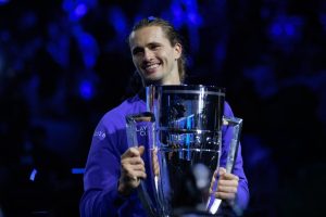 Tennis player smiling and holding the Laver Cup trophy, wearing a purple Team Europe jacket marked "Laver Cup 2026" against a dark blue arena backdrop.