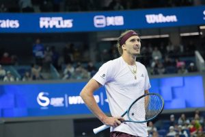 Alexander Zverev in a white shirt and maroon headband holds his racket and grimaces during a match at the Shanghai Masters.