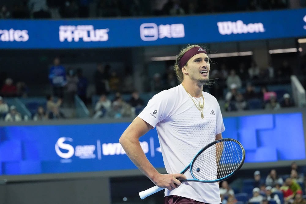 Alexander Zverev in a white shirt and maroon headband holds his racket and grimaces during a match at the Shanghai Masters.