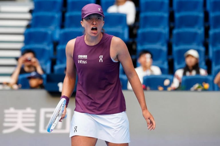 Iga Swiatek in a purple On Infosys top and visor, shouting fiercely during a match at the Wuhan tennis tournament.
