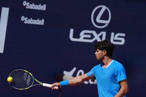 Tennis player in a blue shirt and blue wristband hits a forehand with a yellow-and-black racket, Lexus and Sabadell sponsor boards behind him