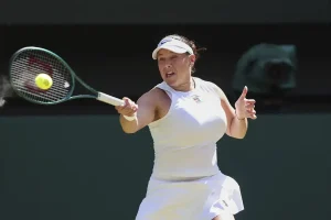 Tennis player in white Nike visor and dress swinging a forehand return at a grass-court event, yellow ball in motion. Likely Amanda Anisimova, per the article.