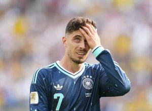 Footballer in navy Germany away kit, number 7, hand on head grimacing during a match, appearing to be Kai Havertz.
