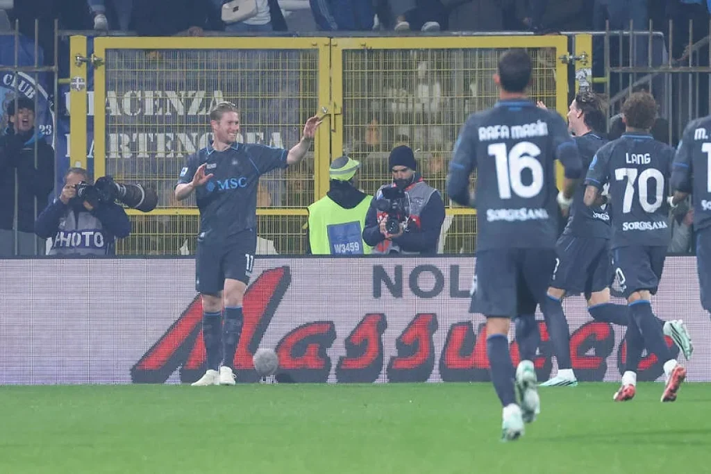 Jogador do Napoli, n.º 11, celebra com os braços abertos enquanto companheiros correm para ele num jogo contra o Monza.