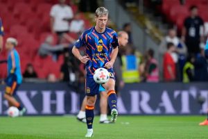 Dani Olmo in Spain kit warming up before a match, juggling a white ball on a pitch in a stadium.