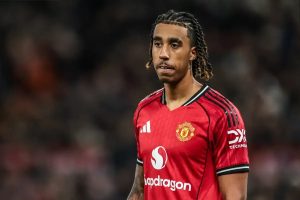 Footballer in red Manchester United home kit with Adidas and Snapdragon sponsors, braided hair, looking to the side during a match