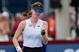 Tennis player in white Red Bull sleeveless top and blue-tinted visor clenching her fist on court, celebrating; Maya Joint at the Korea Open