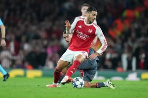 Mikel Merino in Arsenal red and white, battling for the ball on the pitch during a Champions League match at the Emirates.