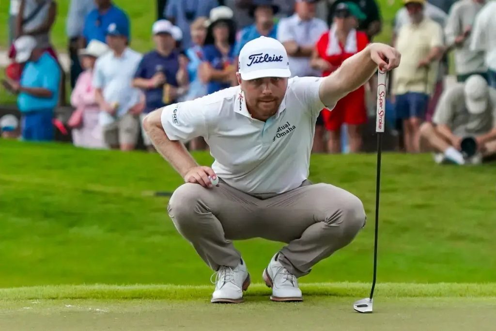 Golfer in white Titleist cap and Hall of Fame-style white polo crouches to read a putt on a green, with spectators behind. Ryan Gerard, Titleist sponsored.