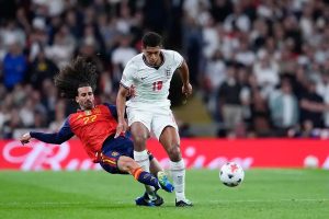 Player in white England No. 18 shirt battling for the ball with a Spain No. 22 player in red during a match at Wembley Stadium.