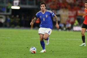 Footballer wearing Italy's blue No. 8 kit dribbling the ball on the pitch during a match against Belgium, Nations League.